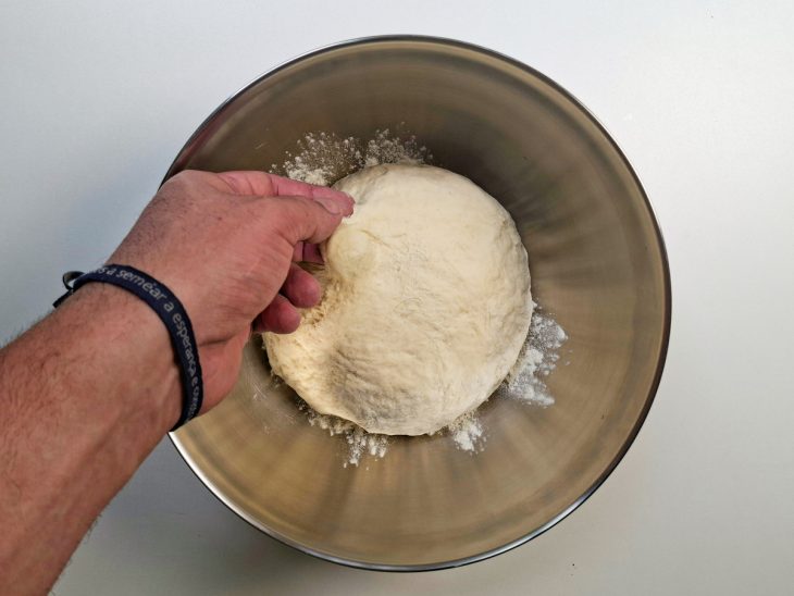 Massa sendo trabalhada até desgrudar das mãos e ficar macia.