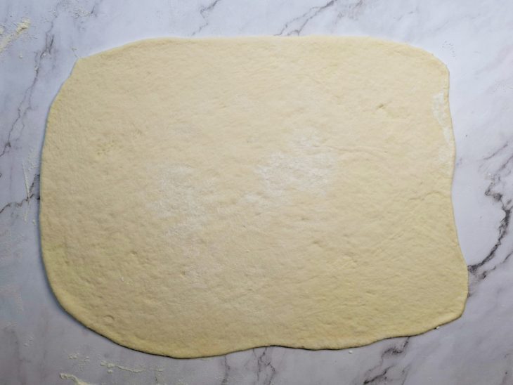 Massa aberta em formato retangular com rolo.