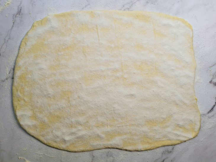 Superfície da massa pincelada com manteiga e polvilhada com açúcar.