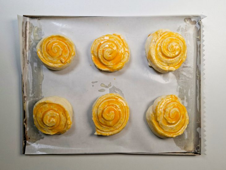 Mistura de gemas com manteiga sendo pincelada sobre as fatias.