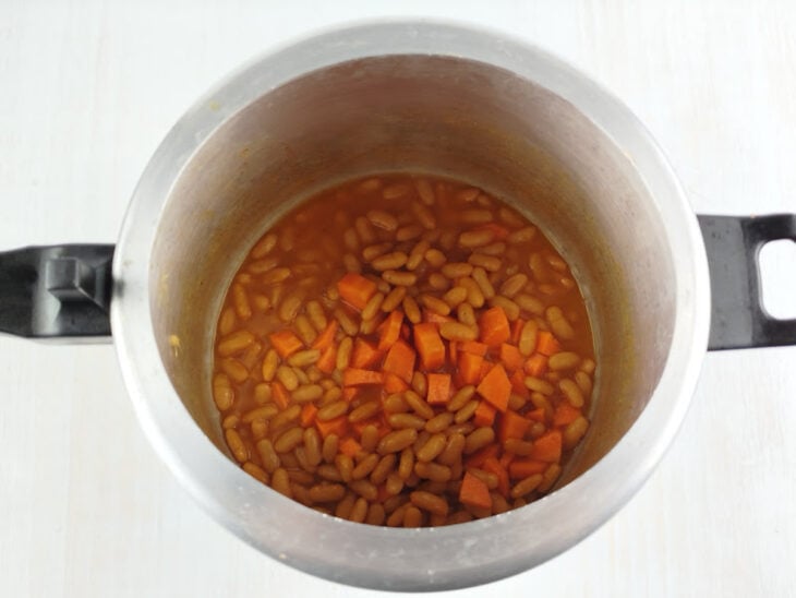 Cebola e alho picados sendo refogados com azeite de oliva até dourarem em uma panela grande.