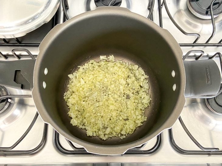 Uma panela de pressão refogando alho e cebola.