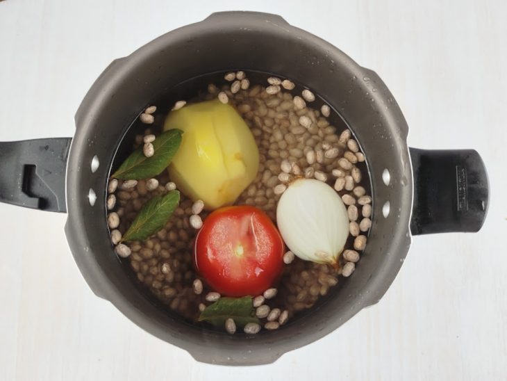Feijão escorrido na panela com tomate, cebola, batata e louro.