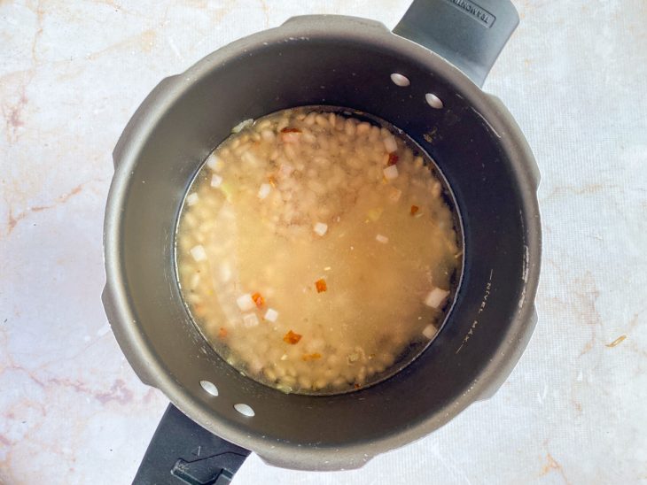 Na panela de pressão, água adicionado para cobrir os ingredientes.