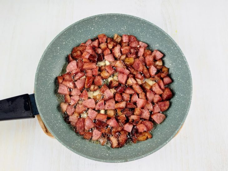 alho picadinho adicionado ao refogado de bacon e calabresa.