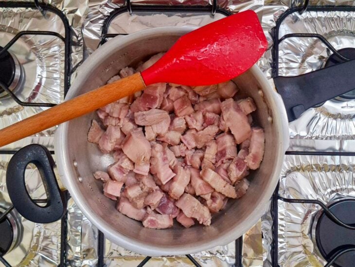 Cubos de panceta fritando na panela de pressão.