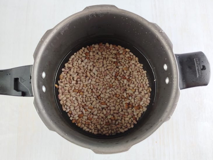 Feijão coberto por água na panela de pressão.