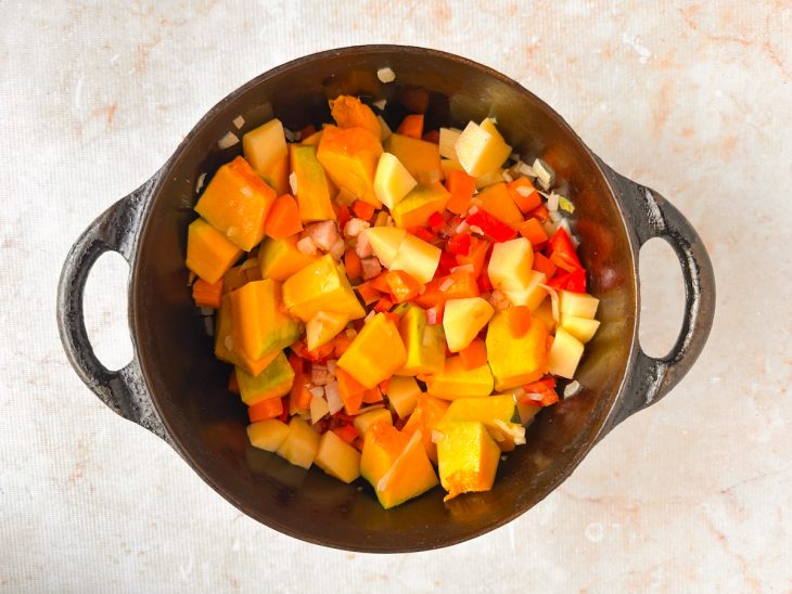 Legumes sendo incorporados ao refogado e mexidos.