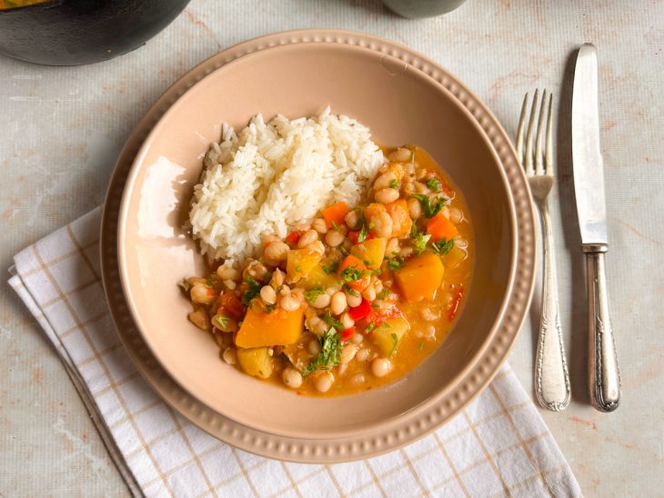 Feijão mulatinho com legumes servido com arroz no prato.