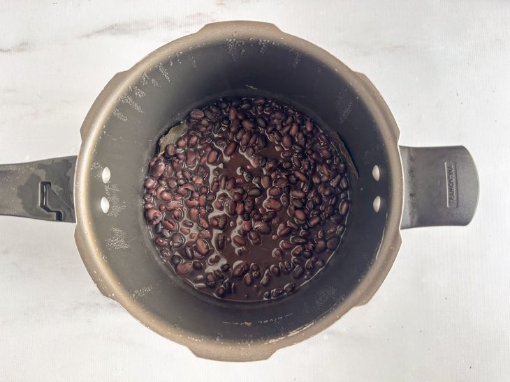 Na panela, feijão já cozido.