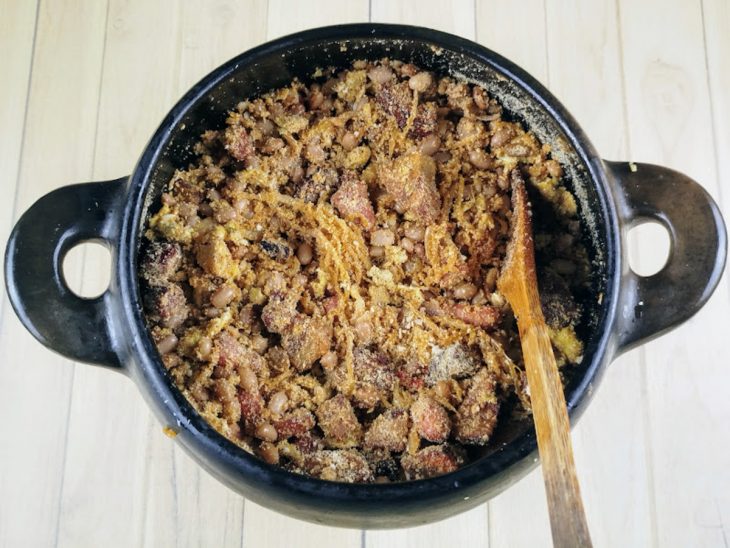 farinha e temperos adicionados ao refogado de feijão tropeiro.