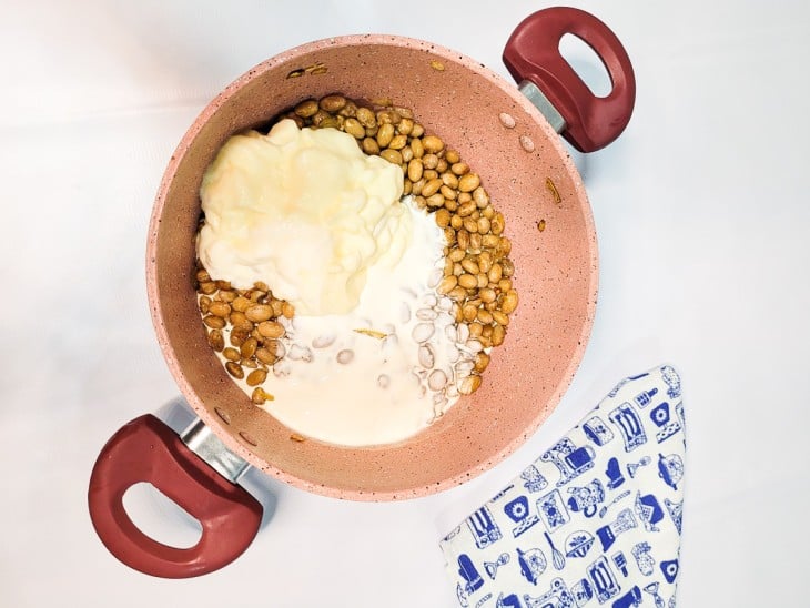 Ingredientes cremosos adicionados à panela com feijão-verde.