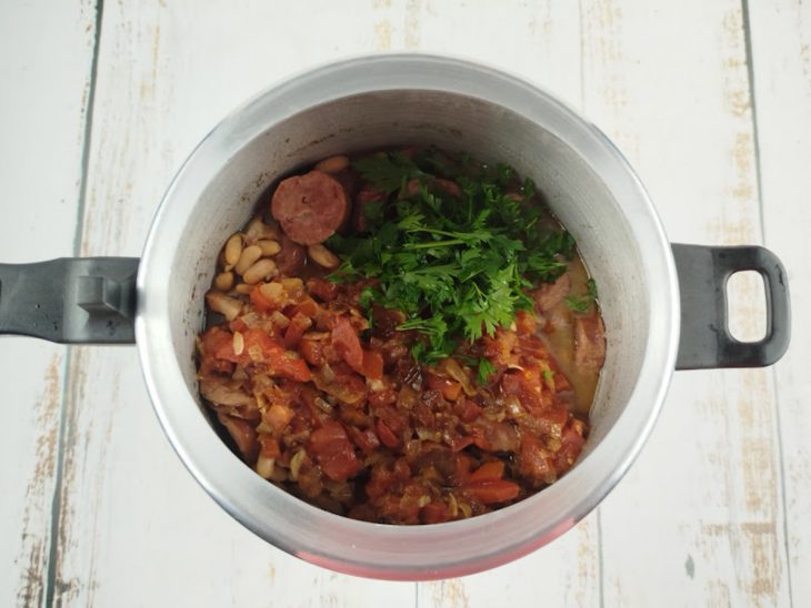 Tempero, coentro e cheiro-verde incorporados à feijoada já cozida.