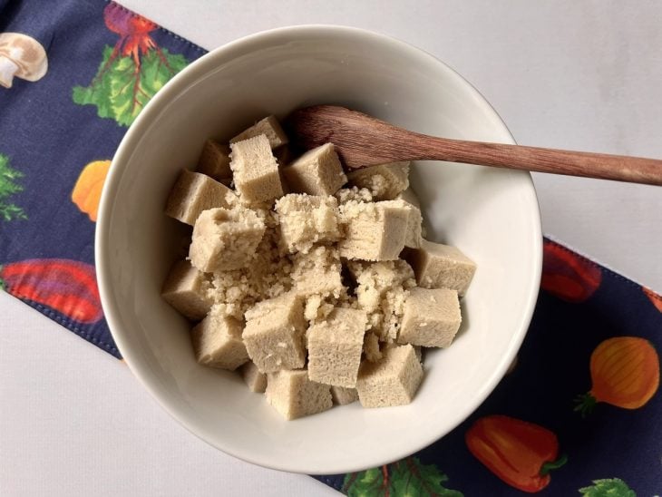 Um recipiente contendo cubos de tofu com alho picado.