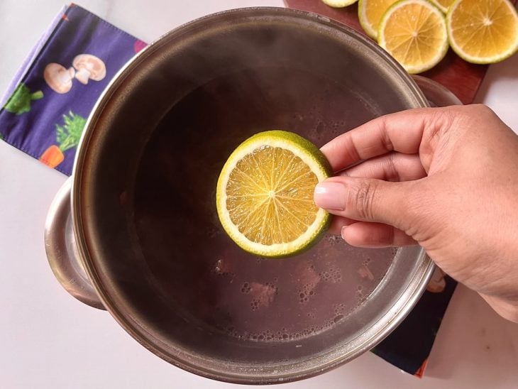 Uma rodela de laranja sendo colocada na feijoada vegana.