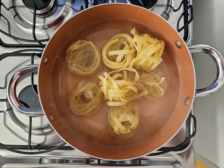 Uma panela com água cozinhando o macarrão fettuccine.