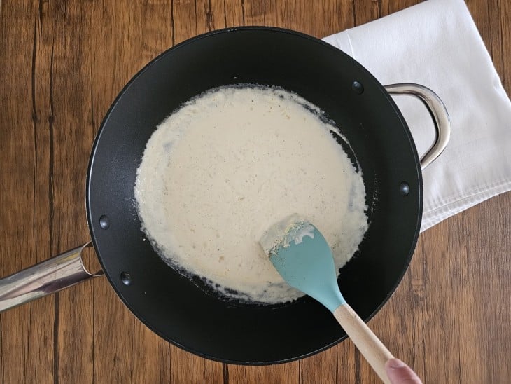 Uma panela com a mistura de molho branco, queijo ralado, noz-moscada e sal.