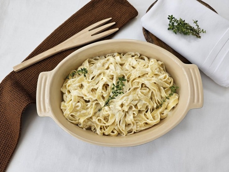 Um recipiente contendo fettuccine alfredo.