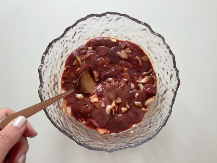 Fígado de galinha sendo temperado em uma tigela com os temperos.
