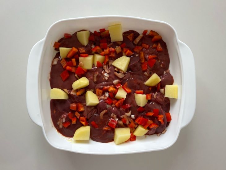 Forma untada com manteiga recebendo o fígado e os legumes distribuídos.