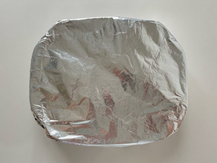 Forma coberta com papel alumínio sendo levada ao forno.