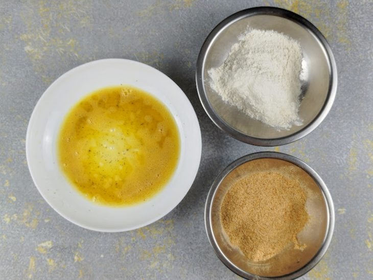 Ovo batido, farinha de rosca e farinha de trigo em recipientes distintos.