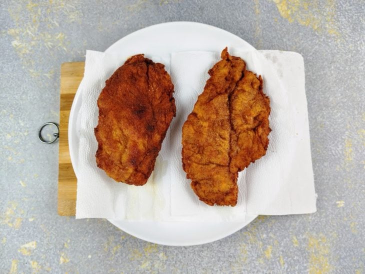 Filés de frango fritos e acomodados em um prato coberto por papel toalha.
