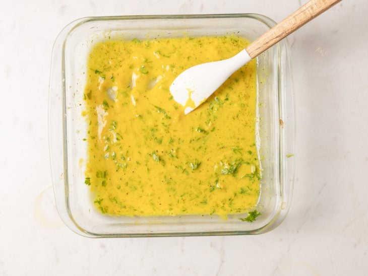 Mostarda, suco do limão, alho picado, salsa, azeite de oliva, sal e pimenta-do-reino misturados em uma tigela de vidro.