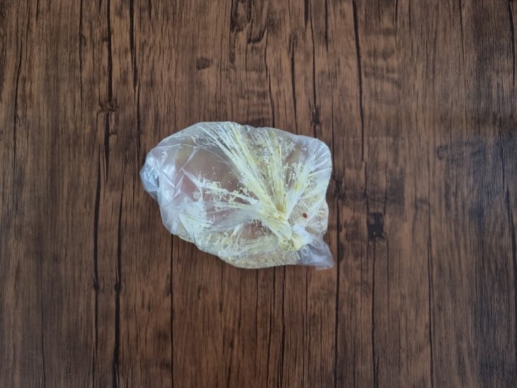 Um saco plástico fechado com uma marinada e os filés de frango.