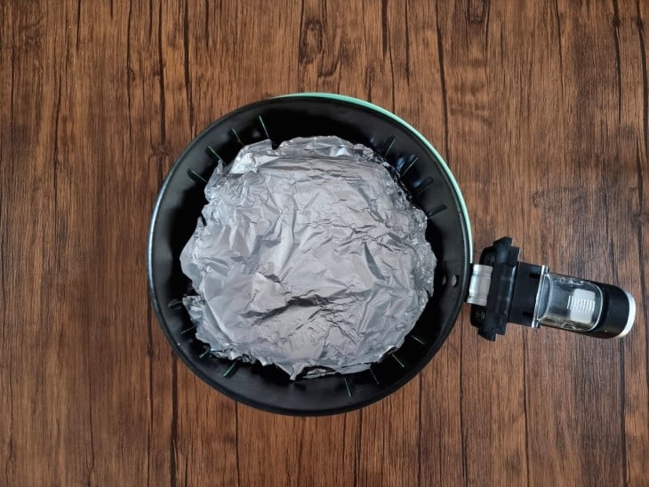 Uma cesta de air fryer forrada com papel alumínio.