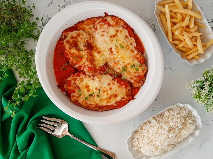 Filé de frango à parmegiana servido com arroz e batata frita.