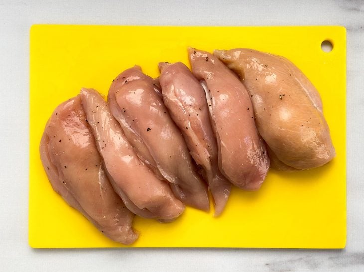 Uma tábua com filés de frango recheados e temperados.