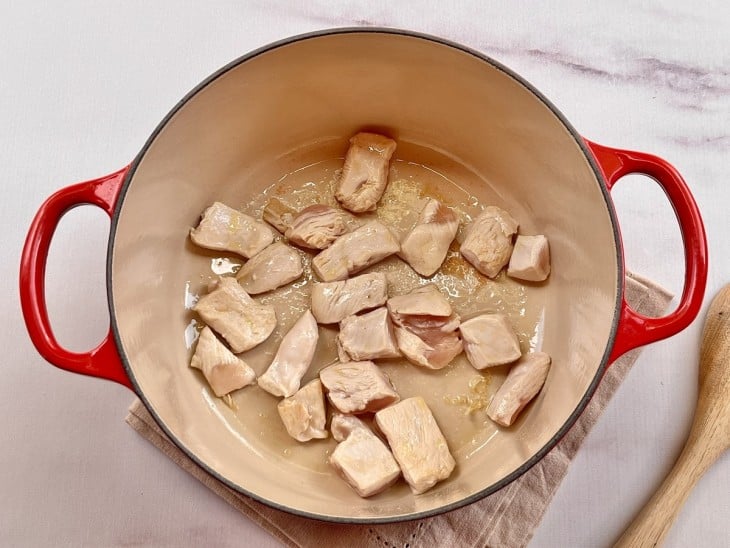 Uma panela com os cubos de frango sendo refogados no azeite.