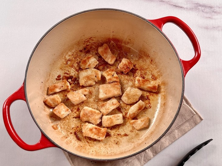 Uma panela com cubos de frango refogados e temperados.