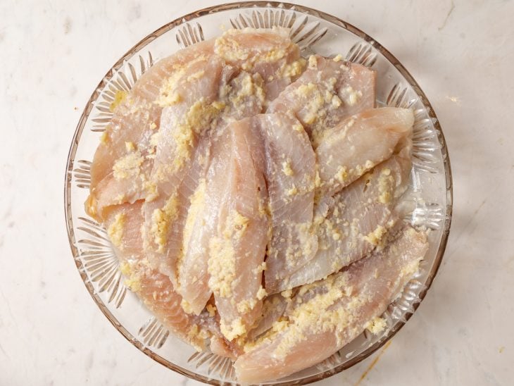 Uma tigela com o peixe temperado e marinando.
