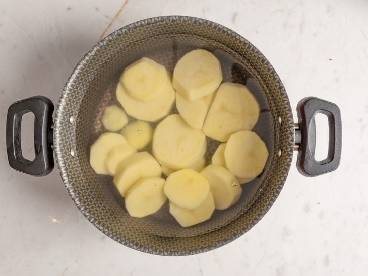 Panela com água e batatas cortadas.