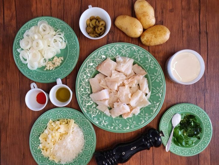 Ingredientes do bacalhau gratinado fácil reunidos na bancada.