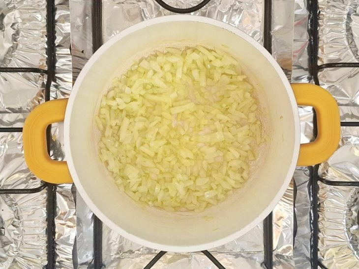 Uma panela ao fogo com a cebola ao dourar.