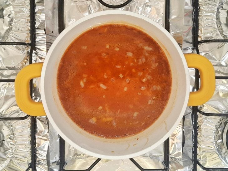 Uma panela com a cebola, o alho e o molho de tomate.