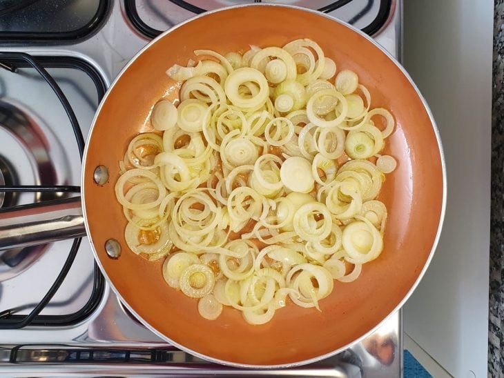 Cebolas sendo fritas em uma frigideira.