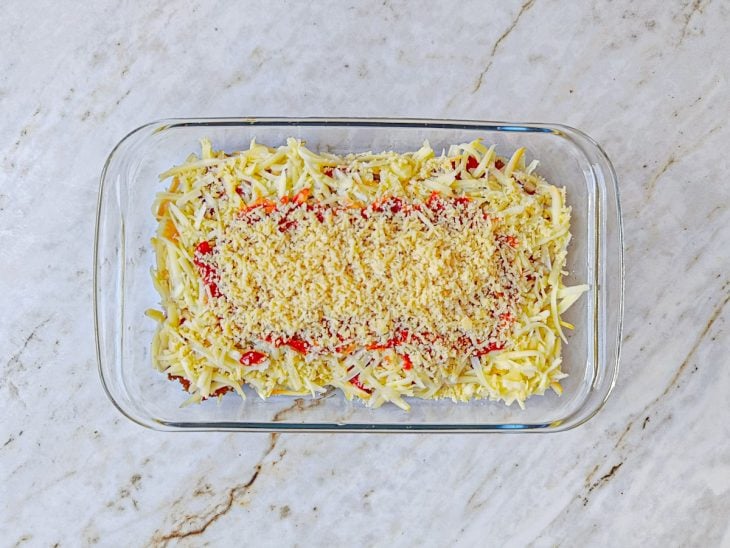 Provolone, parmesão e molho adicionados ao refratário.