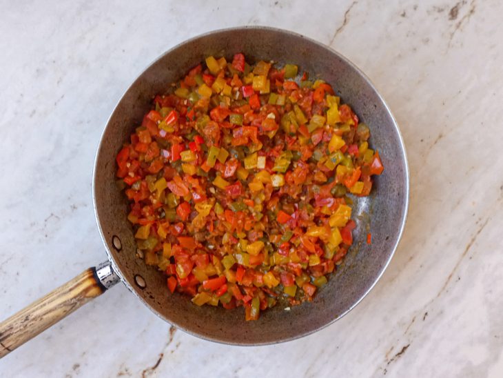 Pimentão, tomate, temperos e água adicionados na frigideira.