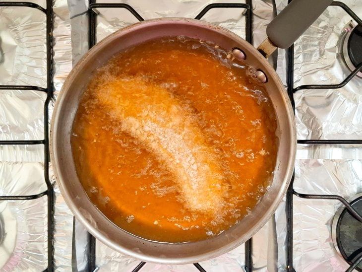 Uma panela com óleo quente e filé a fritar.