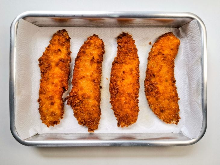 Uma forma forrada com papel-toalha e filés fritos.