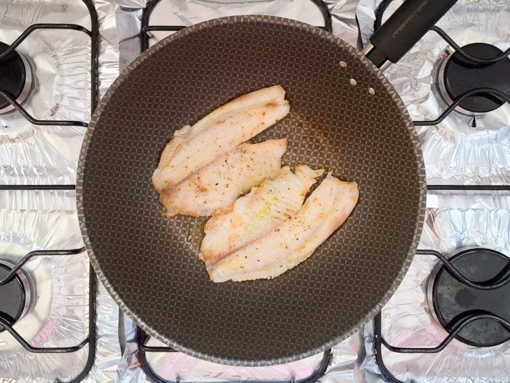 FIlés fritando em uma frigideira com azeite.