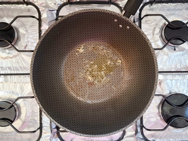 Alho fritando em uma frigideira com manteiga e azeite.