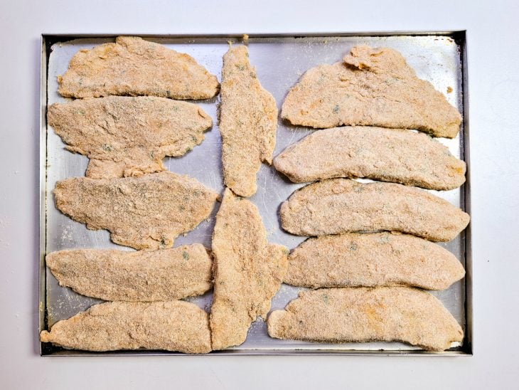 filés de tilápia empanados e organizados para serem fritos.