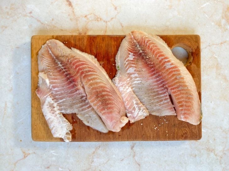 Filés temperados com sal e pimenta-do-reino sobre uma tábua.