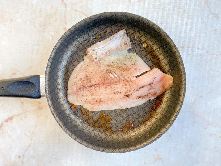 Frigideira com um fio de azeite e filé de tilápia.