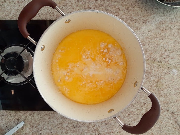 Uma panela branco com alças na cor marrom, com os ingredientes do molho: farinha, manteiga e leite.